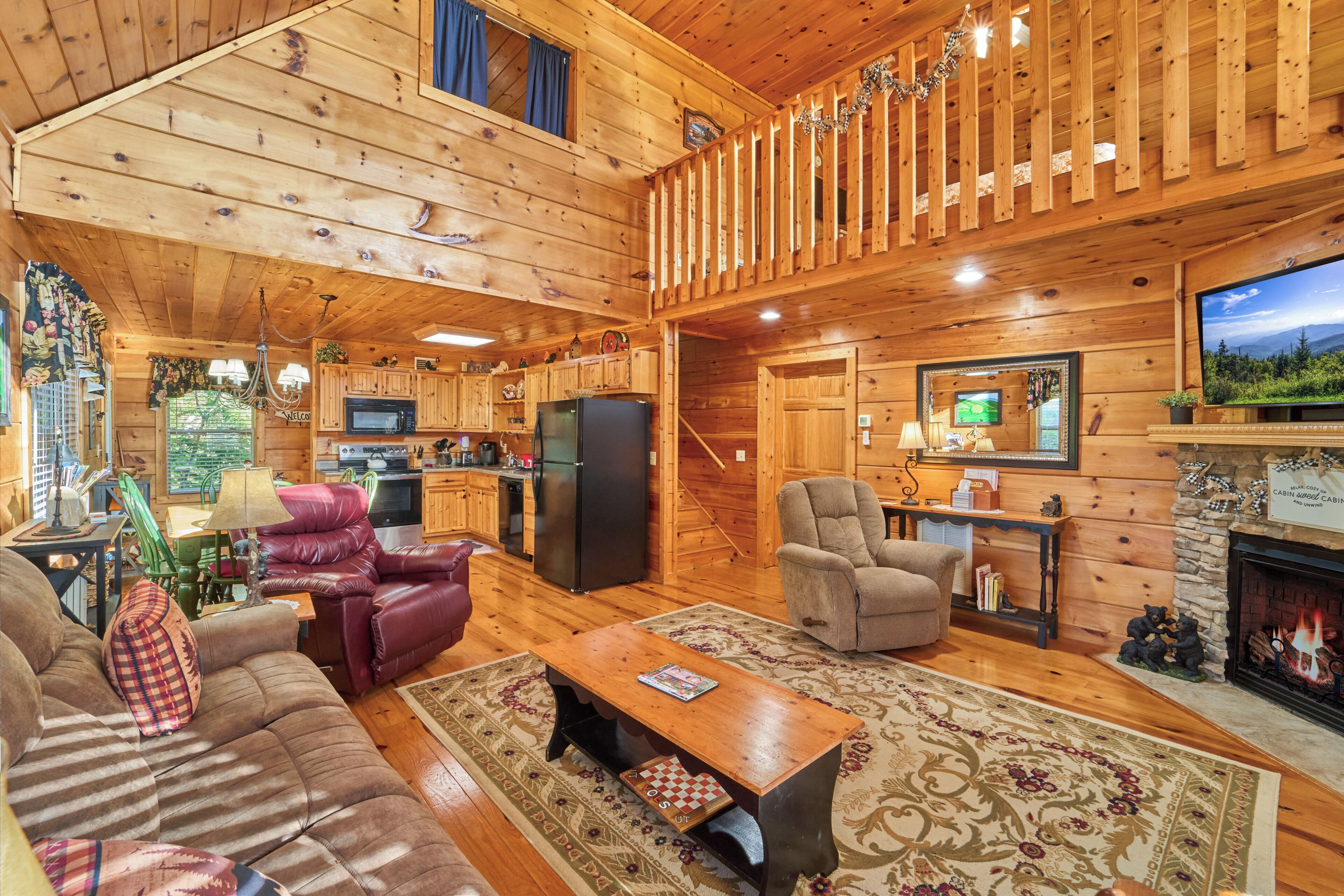 A cabin interior with a living room, kitchen, and a fireplace.