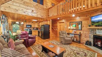 A cabin interior with a living room, kitchen, and a fireplace.
