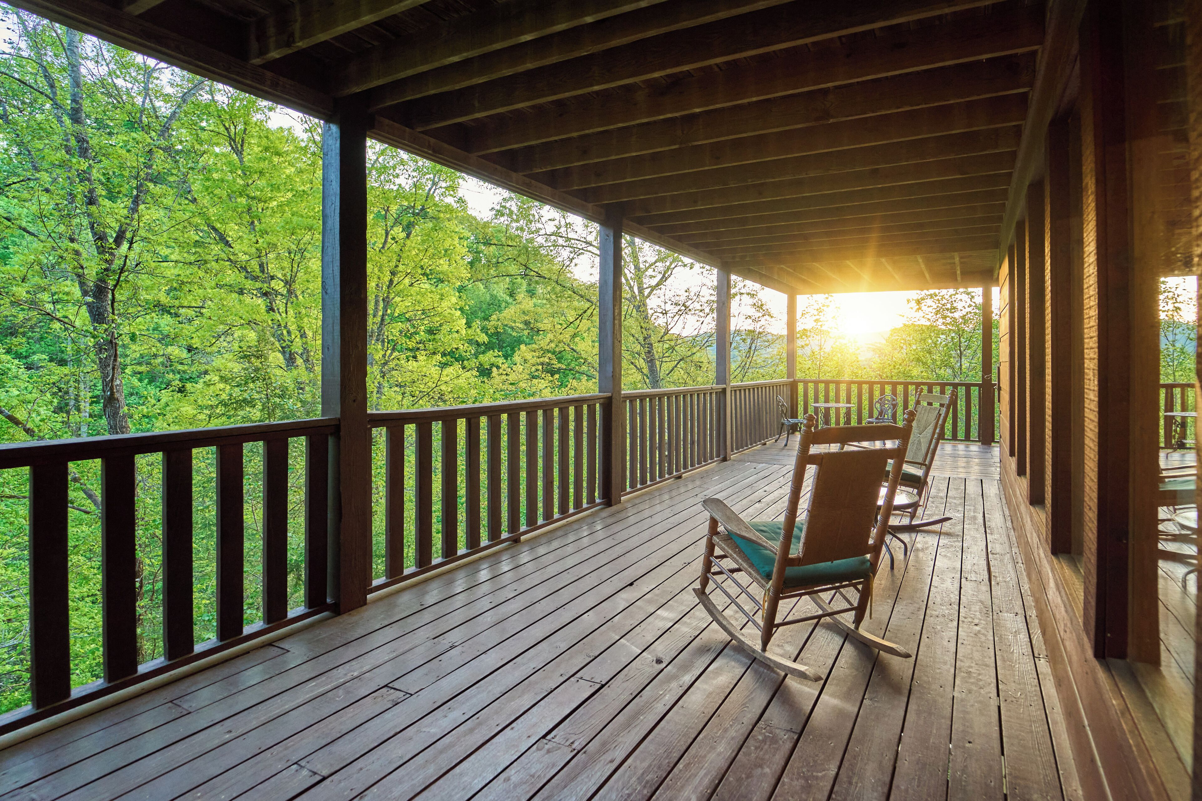 A wooden deck with a railing, overlooking a forested area.