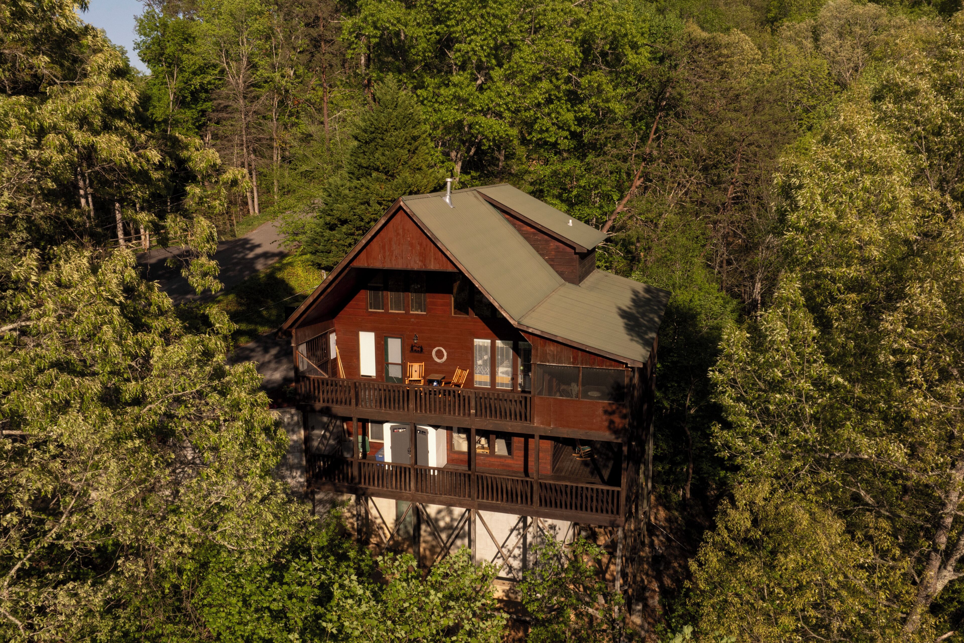 A cabin with a balcony, surrounded by dense forest.