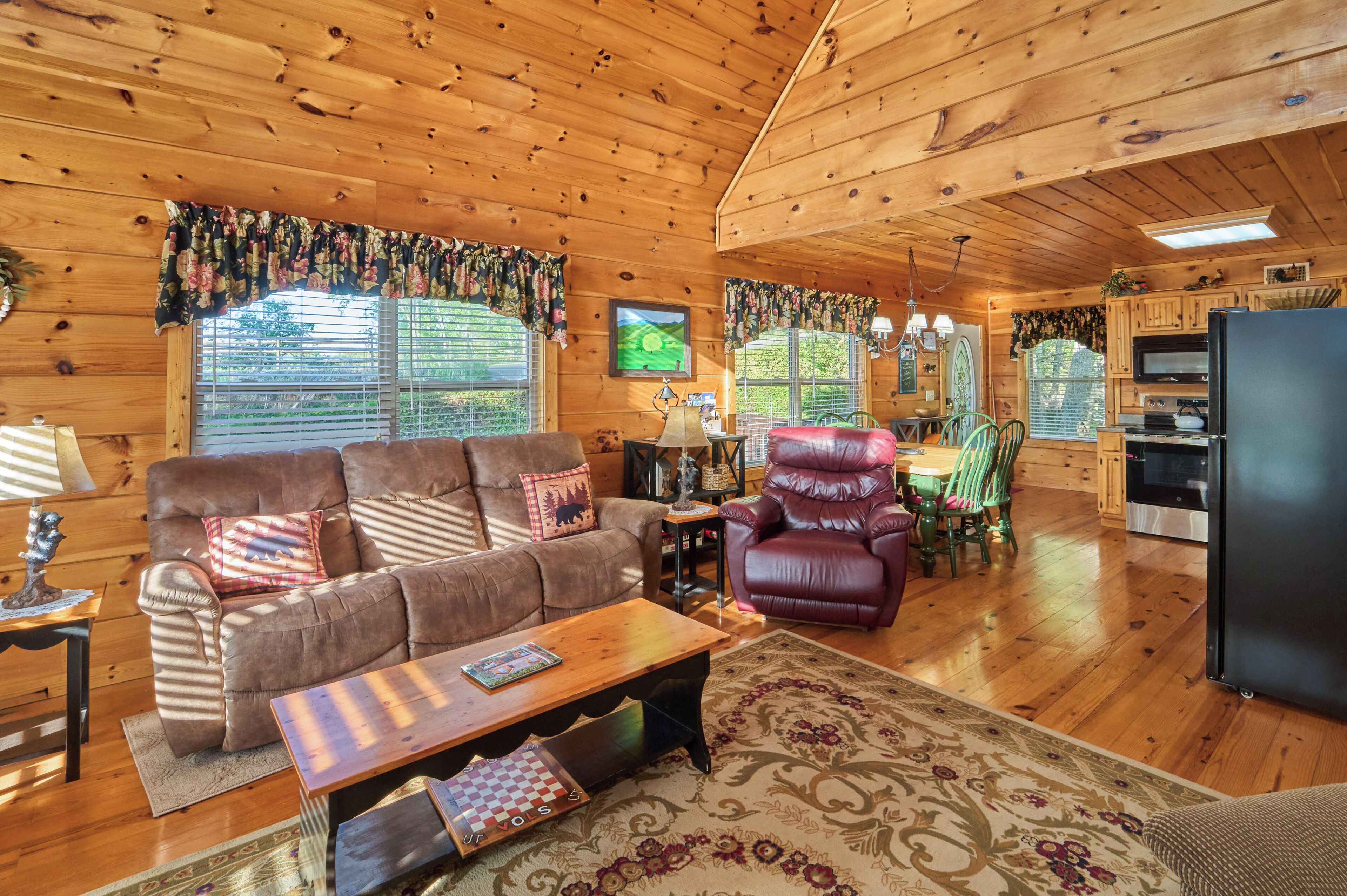 L’intérieur chaleureux d’un chalet avec un plafond en bois, un canapé, une table à manger et un coin cuisine.