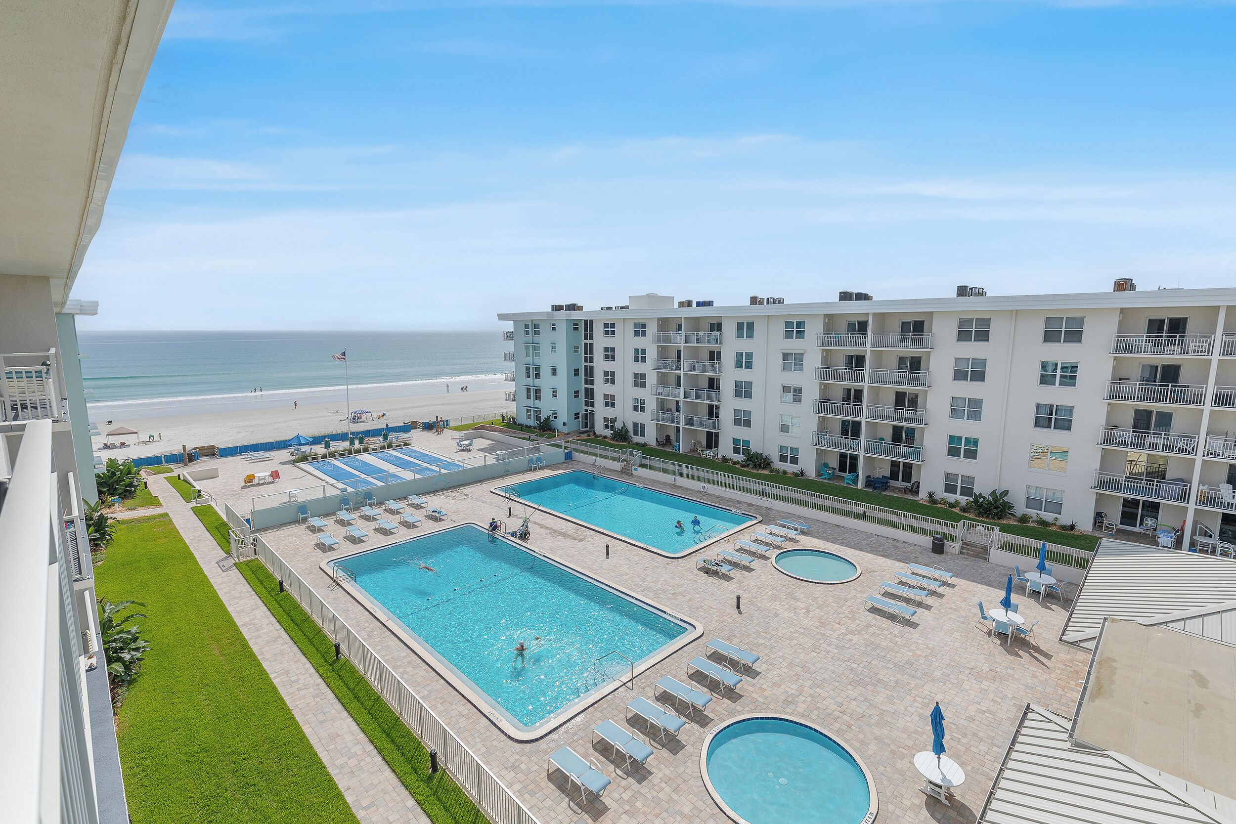 A hotel with multiple swimming pools, a beach, and a view of the ocean.