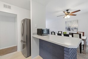 Eine moderne Küche mit einem Einbaukühlschrank, einer Mikrowelle und einem Deckenventilator.