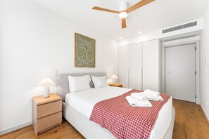 A hotel room with a bed, bedside tables, a ceiling fan, a wardrobe, and a wall-mounted artwork. - GuestReady - Gaia Stay with Pool, Padel & Balcony (Vila Nova de Gaia)