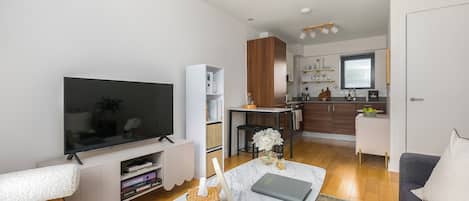 A modern living room with a flat-screen TV, a coffee table, and a sofa.