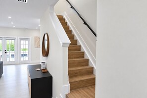 A modern interior with a wooden staircase, a black console table, and a large mirror. - Spectacular Waterfront Home - Coral Lagoon Unit #8 (Marathon)
