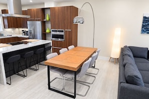 A modern kitchen with wooden cabinets, a built-in oven, and a dining area with a table and chairs. - Spectacular Waterfront Home - Coral Lagoon Unit #8 (Marathon)