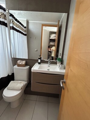 Een badkamer met toilet, wastafel en spiegel.