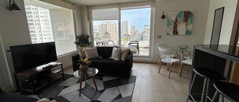 A living room with a sofa, TV, and a dining area with chairs and a table.