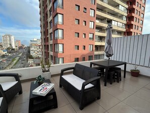 Een balkon met rieten meubels, een tafel en een bloempot.