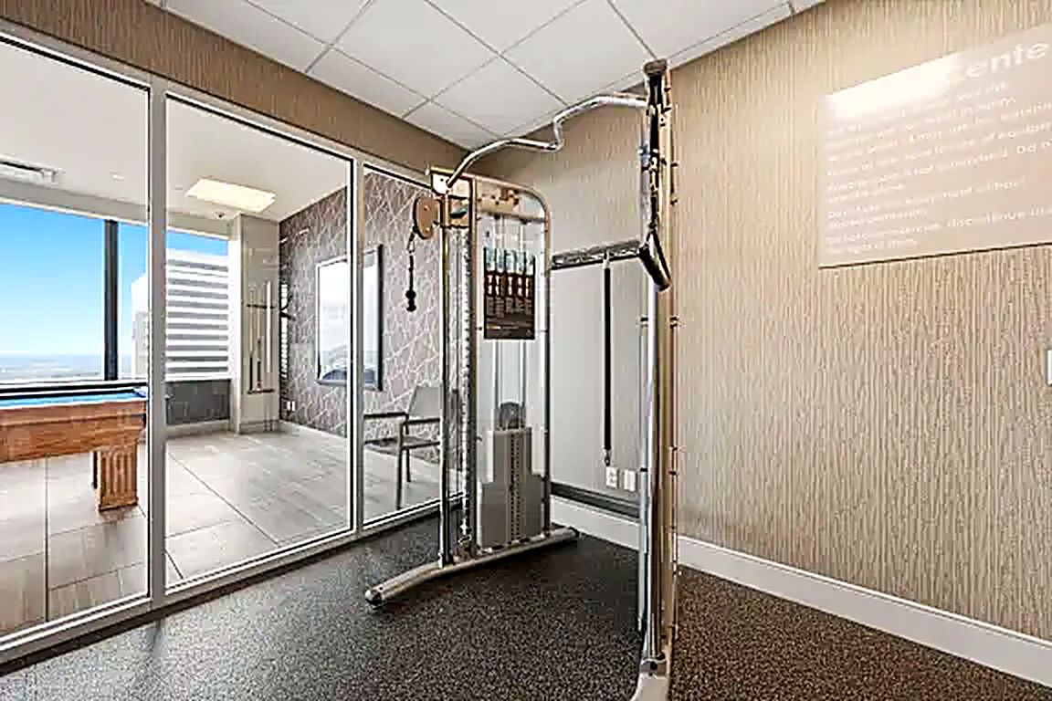 A modern bathroom with a glass shower enclosure, a visible air conditioning unit, and a bench outside the glass door.