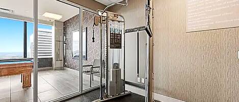 A modern bathroom with a glass shower enclosure, a visible air conditioning unit, and a bench outside the glass door.