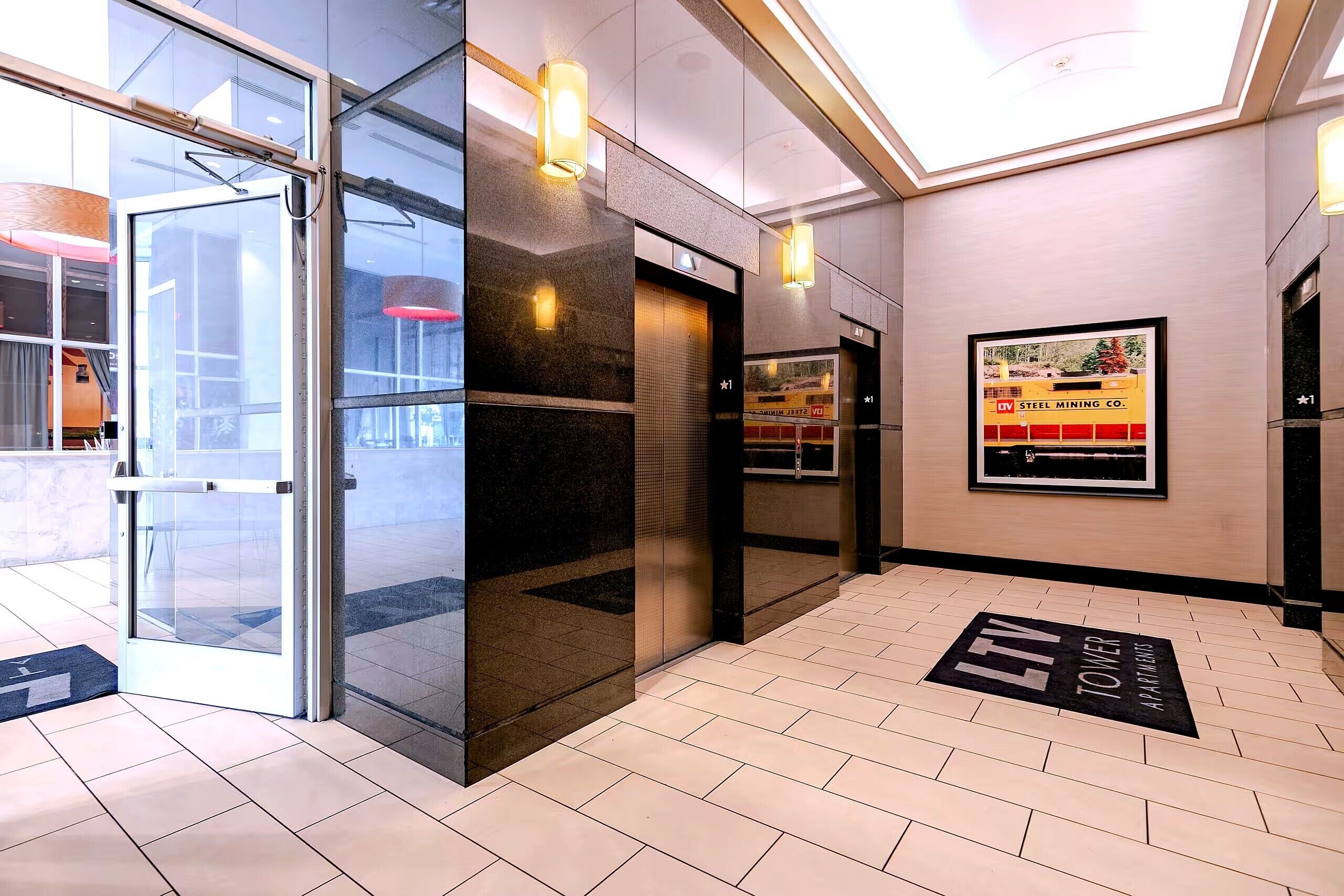 Eine Hotelhalle mit Glastür, einer Rezeption und einem Poster an der Wand.