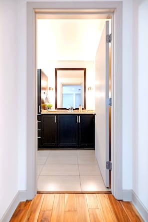 A modern kitchen with dark cabinets, a countertop, and a visible door leading to another room. - Cozy Loft I Downtown High Rise (Dallas)