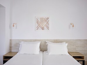 A hotel room with two single beds, a headboard, a wall-mounted artwork, and two wall-mounted light fixtures. - Panthea Resort (Ayia Napa)