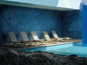 Un espace piscine avec des chaises longues et un mur carrelé.