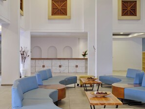 A modern lobby with blue seating, a reception area, and decorative wooden elements. - Panthea Resort (Ayia Napa)