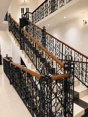 A staircase with ornate black metal railings and wooden handrails, leading to an upper floor. - Marvelous 6-bedroom bed & breakfast in the heart of Kandy (Kandy)