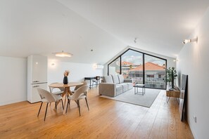 A modern apartment with a dining area, a sofa, and a large window offering a city view. - GuestReady - Joy Apartments - F (Porto)