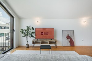 A modern living room with a flat-screen TV, a potted plant, and a framed artwork on the wall. - GuestReady - Joy Apartments - F (Porto)