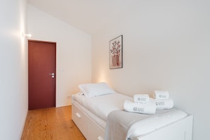 Une chambre à coucher comprenant un lit, une table de chevet, une commode, une porte et une œuvre d’art accrochée au mur.
