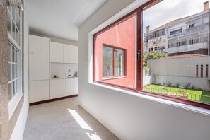 A narrow hallway with a window, a kitchenette, and a view of a building with balconies. - GuestReady - Joy Apartments - D (Porto)