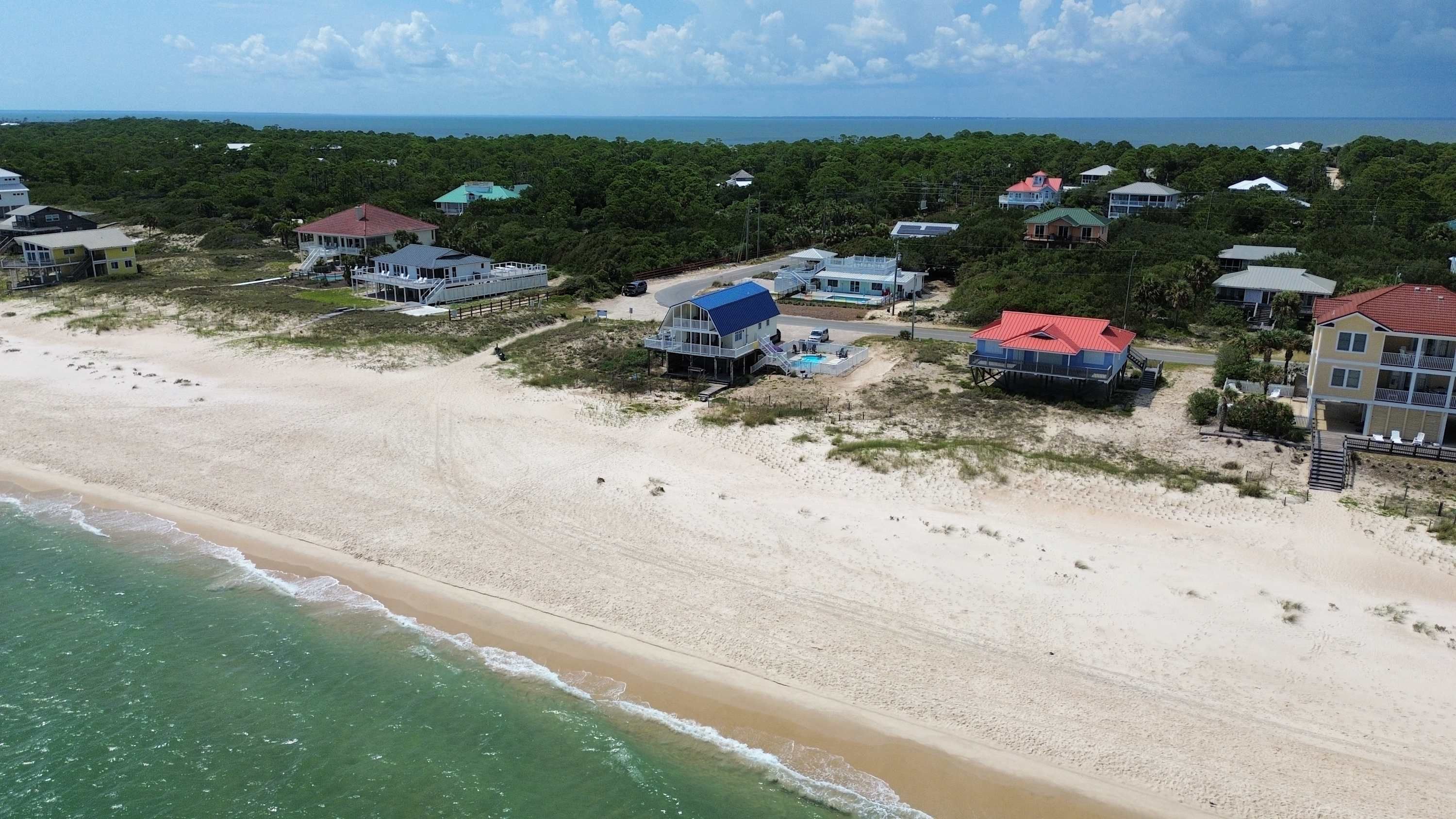 A coastal property with beachfront villas, a swimming pool, and a view of the ocean.