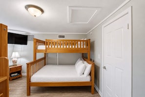 A bunk bed room with a desk, lamp, and a door. - Just Beachy, Private Pool, Beach Front (Saint George Island)