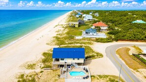 A beachfront property with a swimming pool, a covered deck, and a road curving around the property. - Just Beachy, Private Pool, Beach Front (Saint George Island)