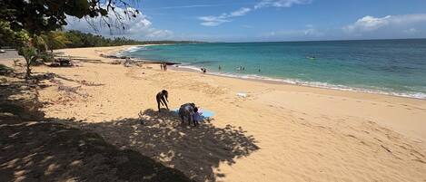 Ein Strand mit blauem Himmel, ruhiger See und einigen Personen.