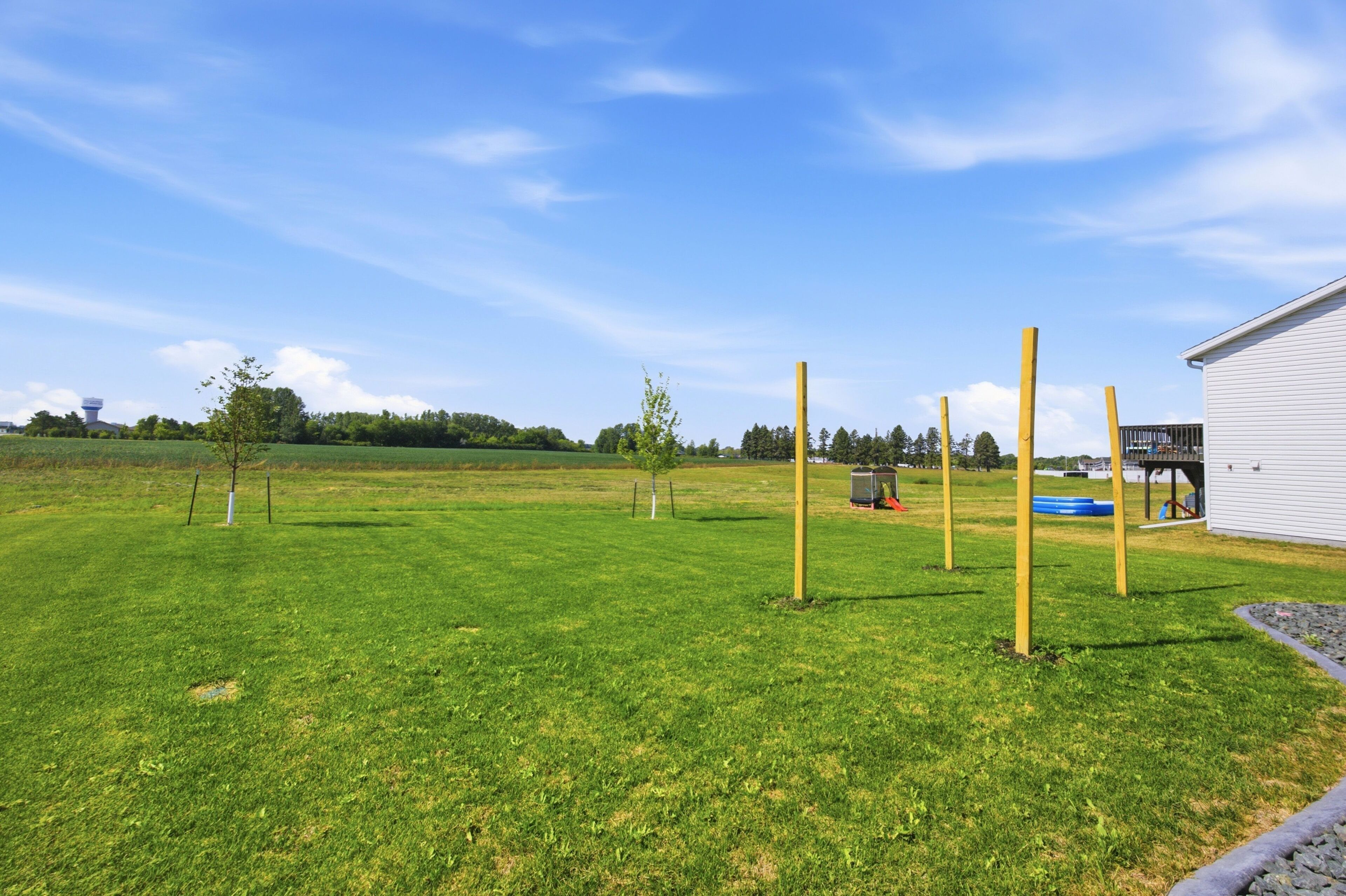 A grassy field with a white building and a water tower in the distance.