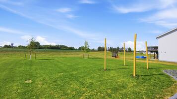 A grassy field with a white building and a water tower in the distance.