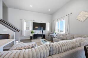 Una sala moderna con un conjunto de sofá, un televisor de pantalla plana y una escalera.
