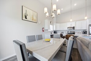 A modern kitchen with white cabinets, a dining table with chairs, and a chandelier. - Modern Horace Retreat for Fargo Adventures (Horace)