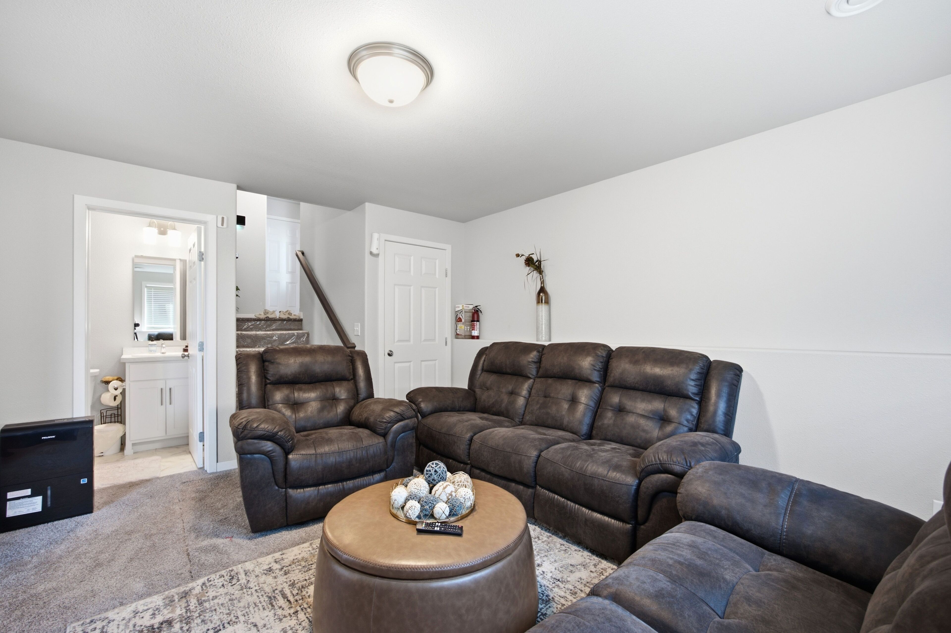 A living room with a sectional sofa, ottoman, and a small table with decorative items.