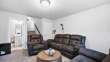 A living room with a sectional sofa, ottoman, and a small table with decorative items.