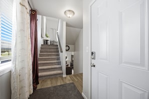Una escalera conduce a un segundo piso con una puerta a la derecha y una ventana a la izquierda.