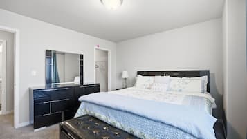 A bedroom with a bed, a dresser, a mirror, and a ceiling light.