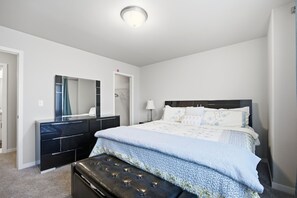 A bedroom with a bed, a dresser, a mirror, and a ceiling light. - Modern Horace Retreat for Fargo Adventures (Horace)