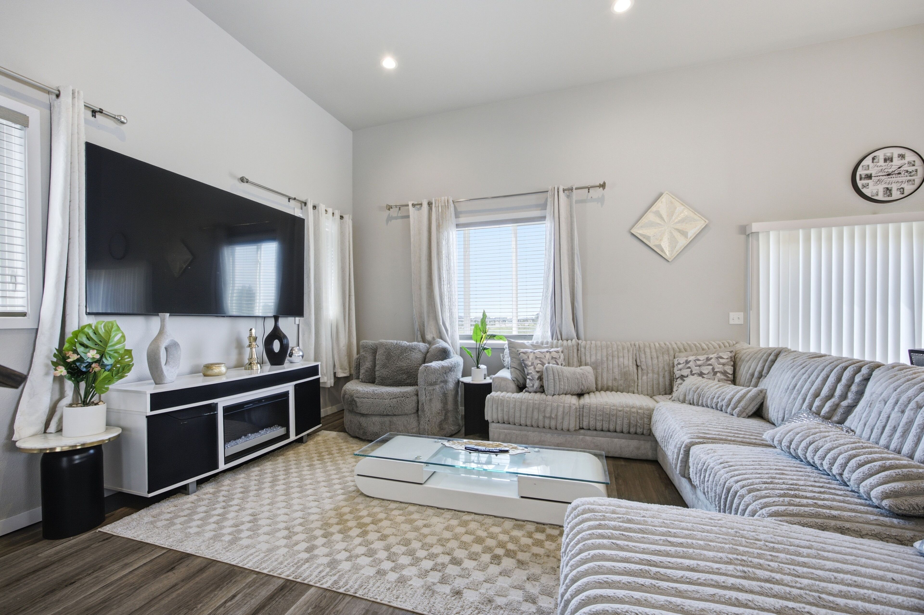 A modern living room with a flat-screen TV, a sofa set, a coffee table, and a decorative wall piece.