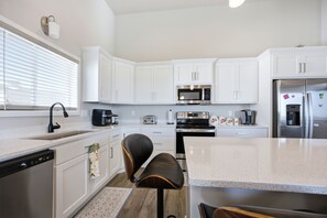 A modern kitchen with white cabinetry, a stainless steel refrigerator, a microwave, and a coffee maker. - Modern Horace Retreat for Fargo Adventures (Horace)