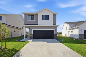 A two-story residential building with a garage, a covered porch, and a well-maintained lawn. - Modern Horace Retreat for Fargo Adventures (Horace)