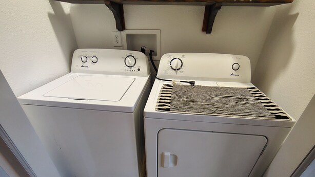 A laundry area with two white appliances, one with a flat surface and the other with a patterned top.