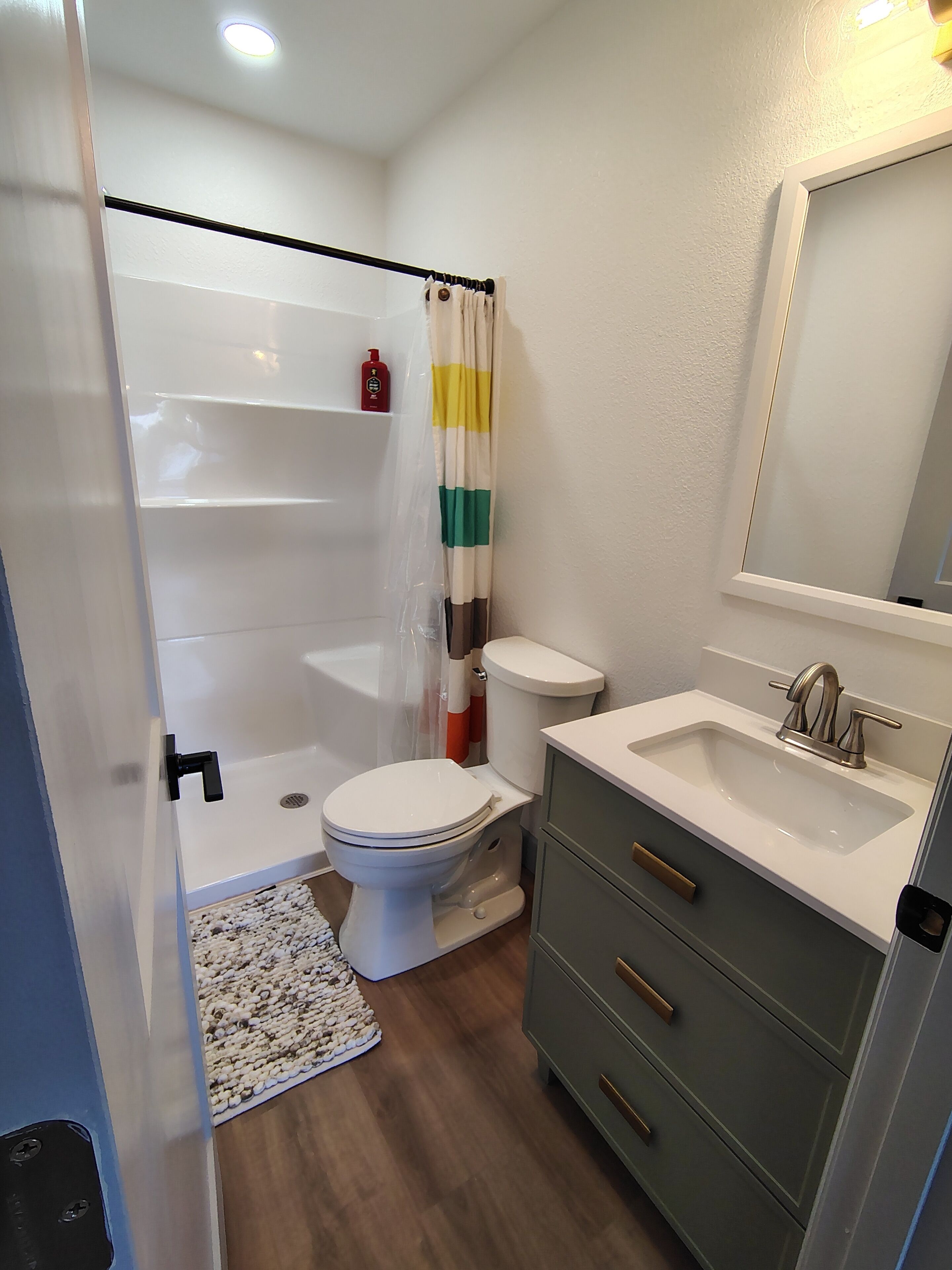 Une salle de bain équipée d’une douche, de toilettes, d’un lavabo et d’un miroir.