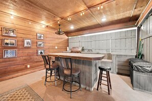 A kitchen with wooden walls, a bar area with stools, and a grill. - Hebron Estate-POOL-Movie Room-3 Mi to The Amp (Rogers)