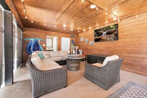 A wooden interior with wicker furniture, a round table, and a wall-mounted picture. - Hebron Estate-POOL-Movie Room-3 Mi to The Amp (Rogers)