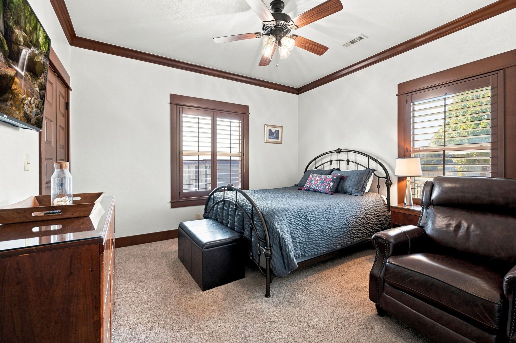 A bedroom with a bed, a desk, a chair, a window, and a ceiling fan.