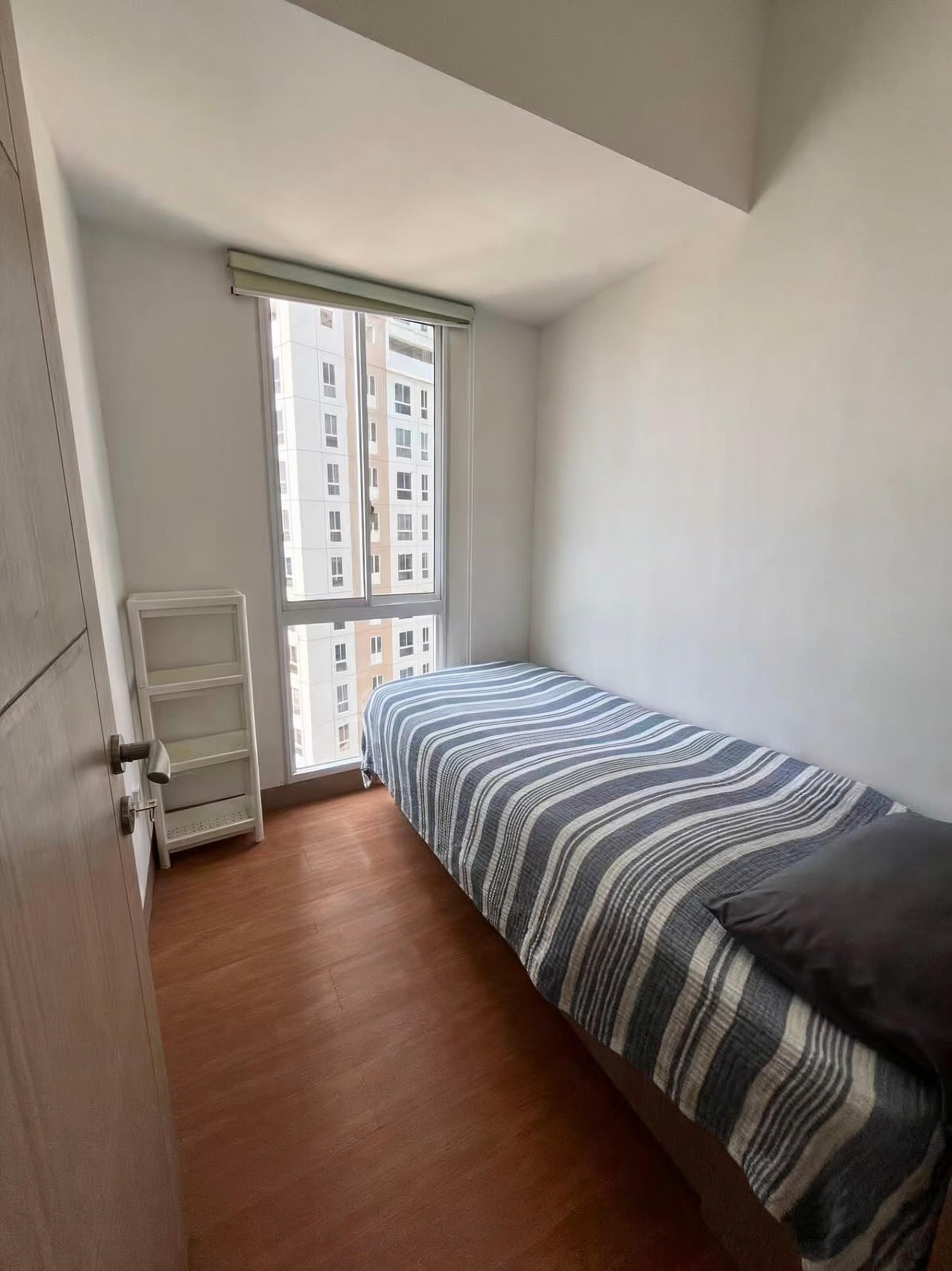 A bedroom with a bed, a window, and a door.