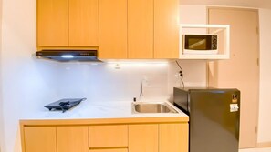 A compact kitchen with wooden cabinets, a built-in microwave, a sink, and a refrigerator. - Tokyo Riverside Ocean Pearl Apartment (kabupaten Tangerang)