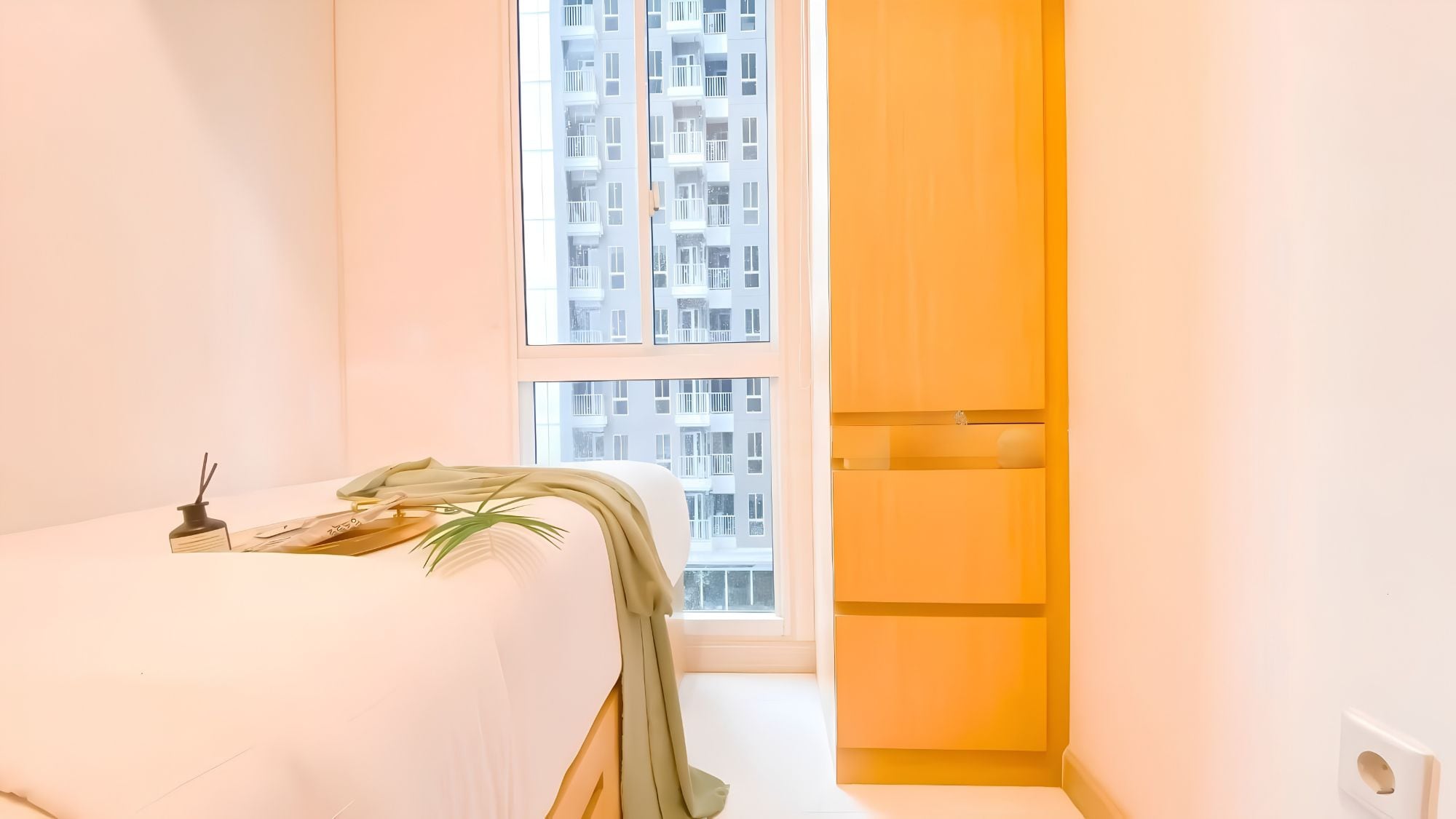A bedroom with a bed, a window, and a wooden wardrobe.